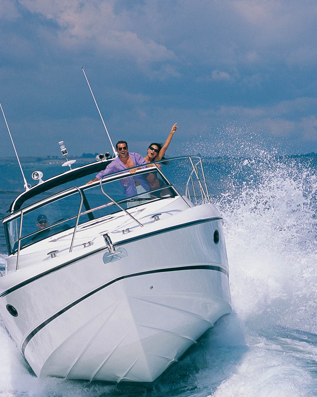 A couple on board a Princess V42 at high speed on the water, the woman is punching her fist in the air with joy