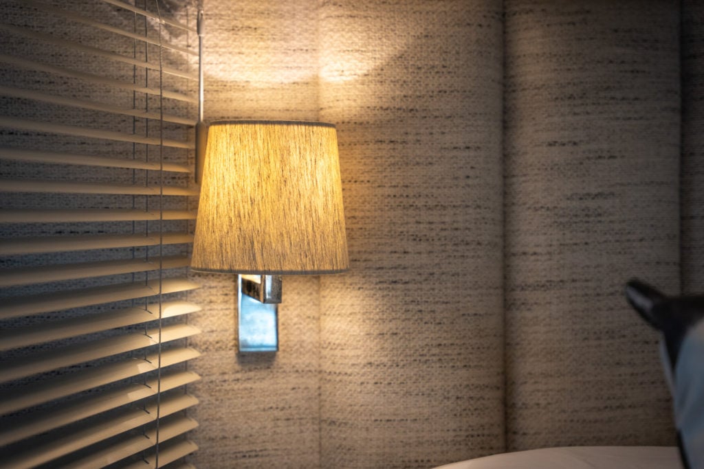 Interior yacht lighting Up close of a fitted sconce to the grey fabric headboard of a yacht double bed